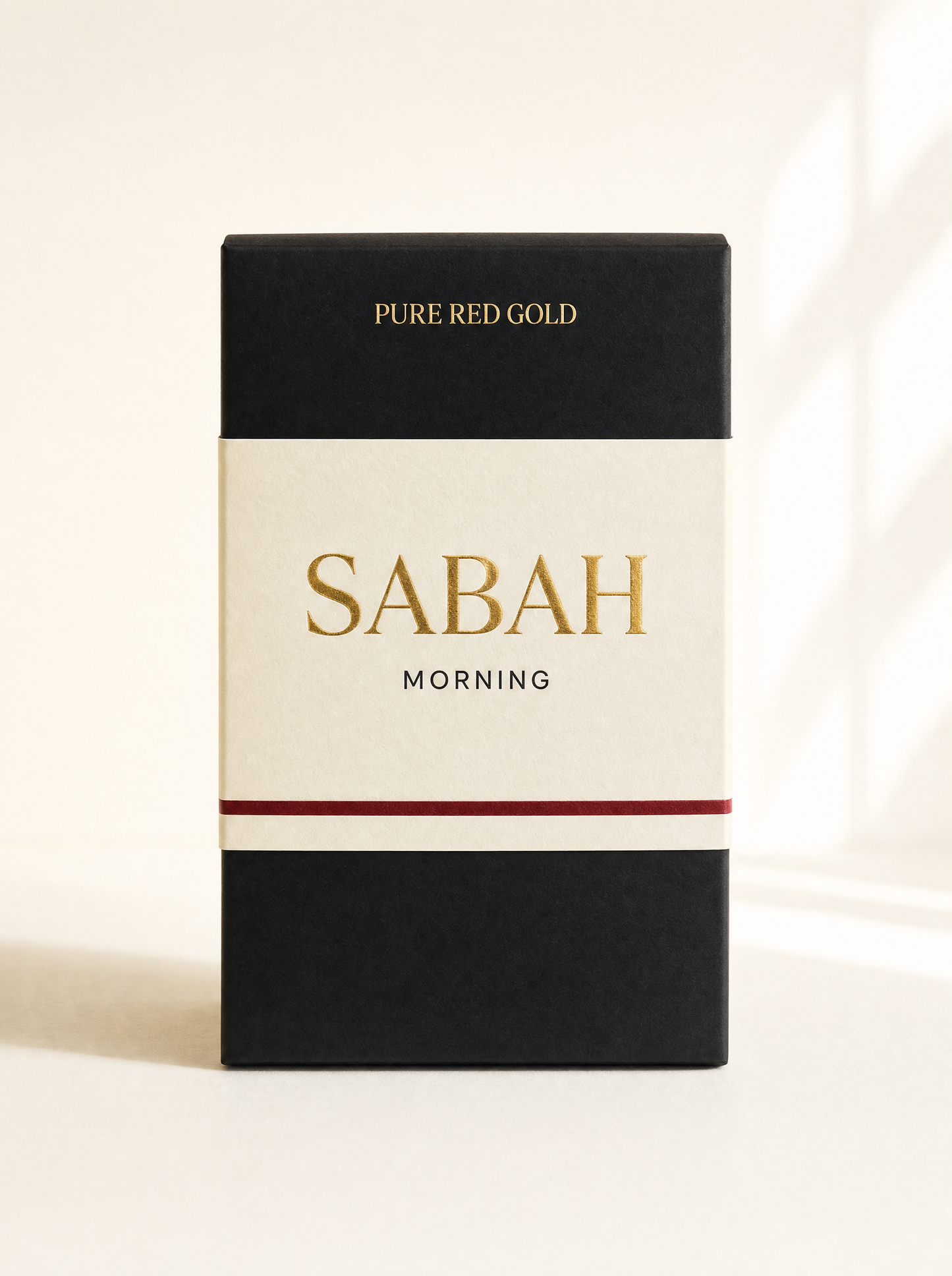 Sabah herbal tea box — matte black with cream band, gold serif SABAH and MORNING, on warm ivory
