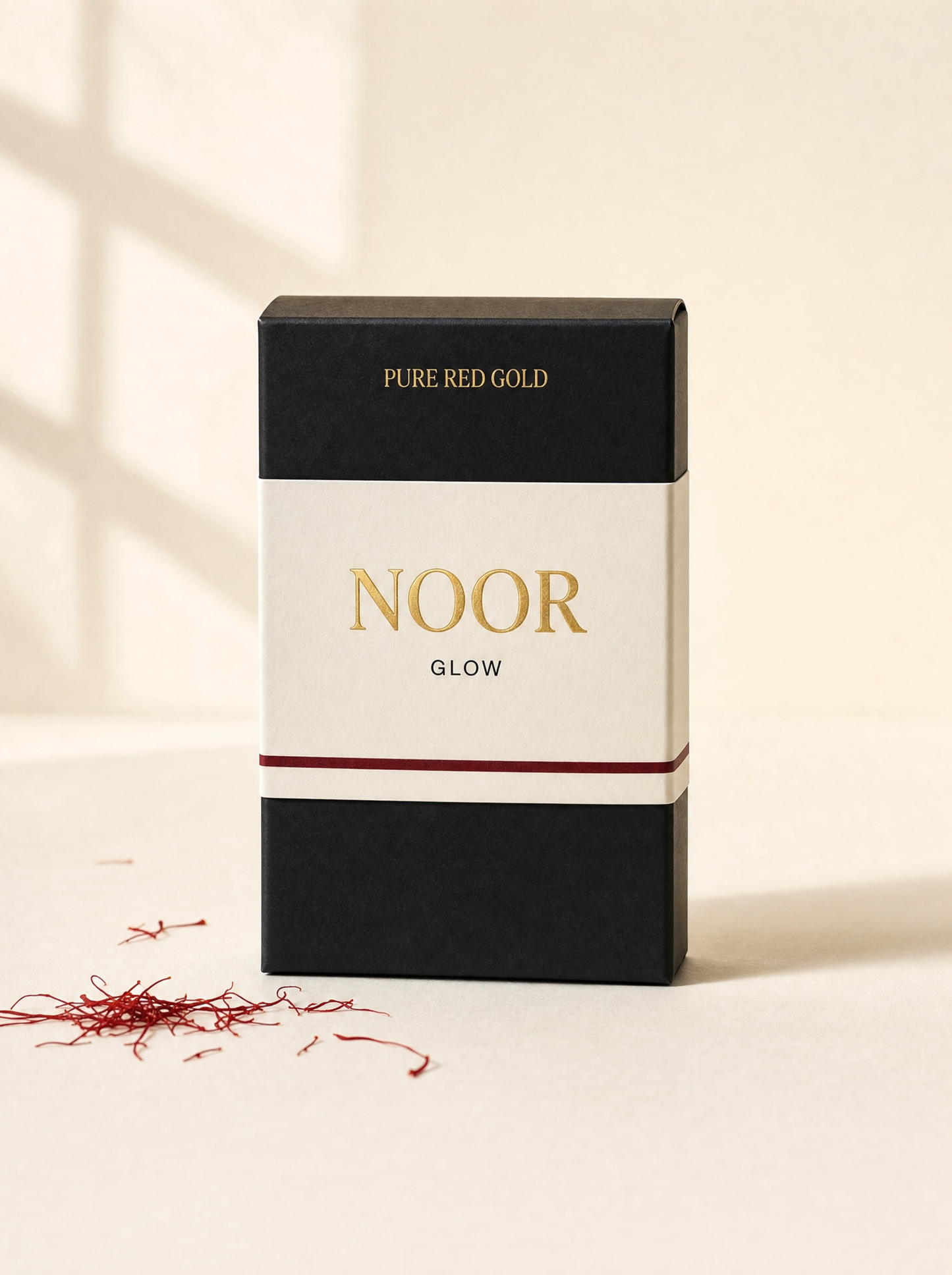 Noor herbal tea box — matte black with cream band, gold serif NOOR and GLOW, on warm ivory