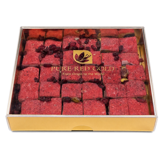 Gold gift box with a clear lid holding rose-red Signature Red Berry delights, the PURE RED GOLD lockup printed in gold on the lid, on white