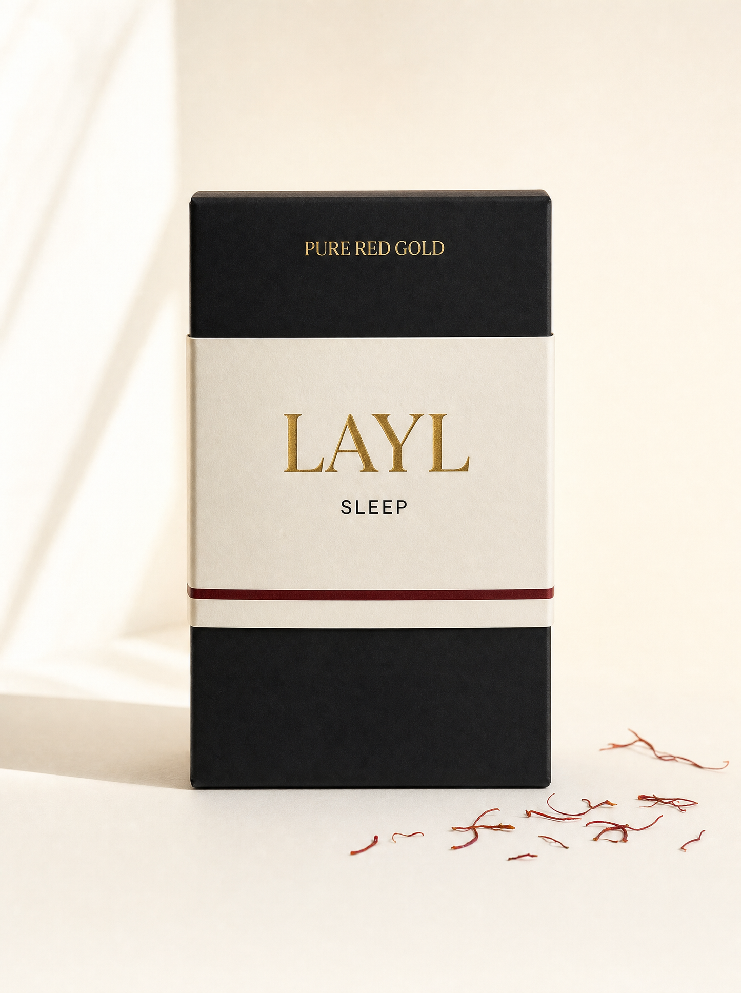 Layl herbal tea box — matte black with cream band, gold serif LAYL and SLEEP, on warm ivory
