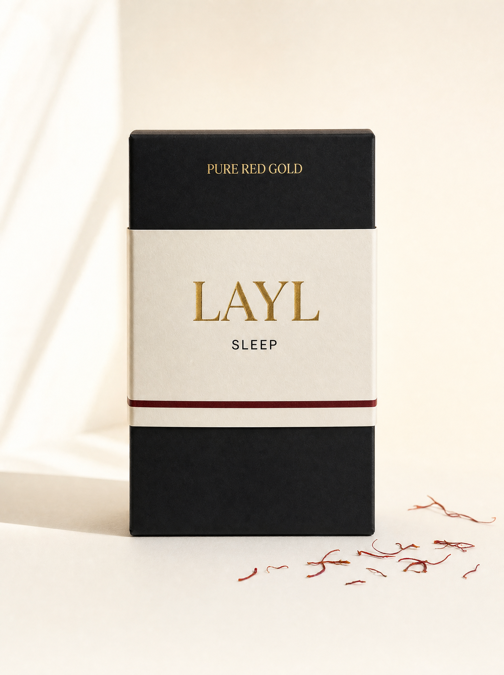 Layl herbal tea box — matte black with cream band, gold serif LAYL and SLEEP, on warm ivory