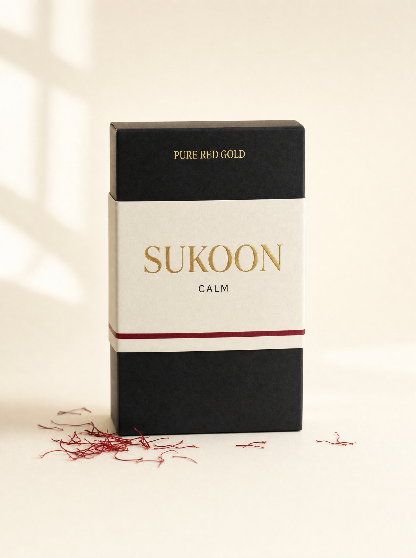 Sukoon herbal tea box — matte black with cream band, gold serif SUKOON and CALM, on warm ivory