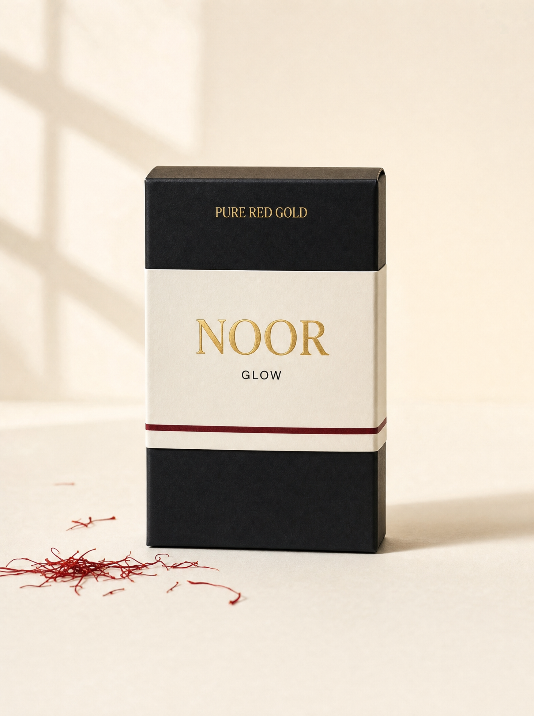 Noor herbal tea box — matte black with cream band, gold serif NOOR and GLOW, on warm ivory