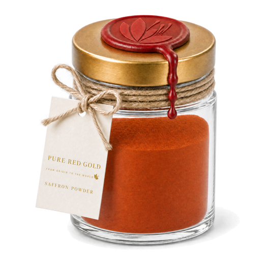 Clear glass jar of milled saffron powder with a brushed gold screw lid, crimson wax medallion embossed with the crocus, jute twine and a cream hang tag reading PURE RED GOLD - FROM ORIGIN TO THE WORLD - SAFFRON POWDER, on white