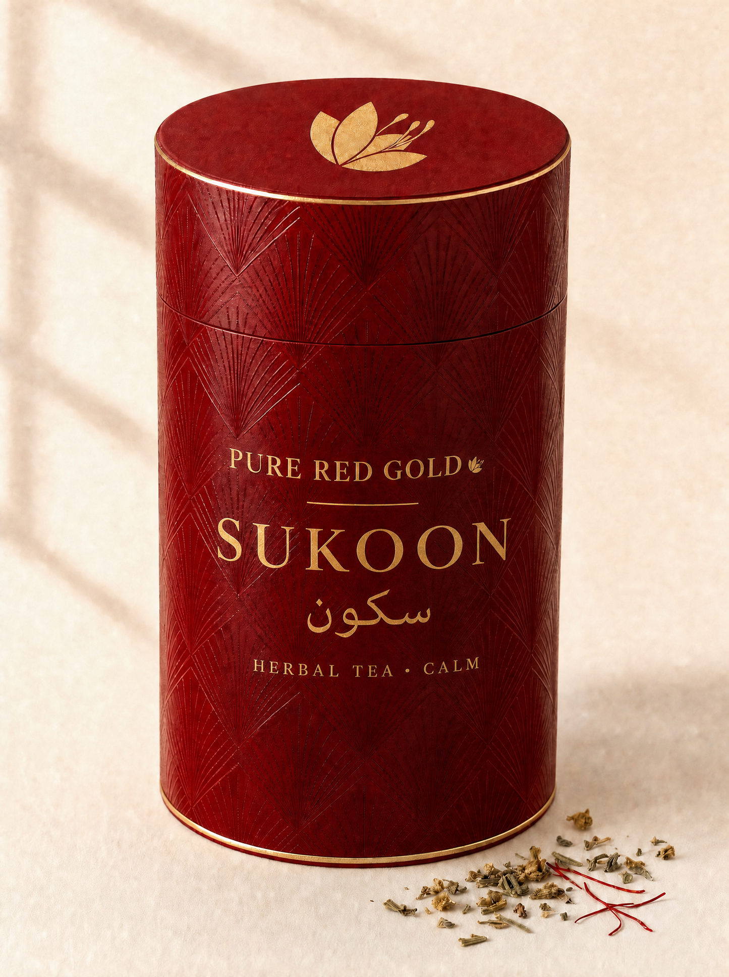 Sukoon herbal tea — a crimson cylinder tube with a tone-on-tone pattern, gold foil rims, the saffron crocus on the lid, and PURE RED GOLD above SUKOON with its Arabic name in gold foil